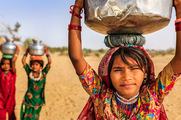 girls carrying large pots on their heads